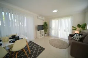 Modern open-plan living and dining space with neutral tones and vertical blinds.