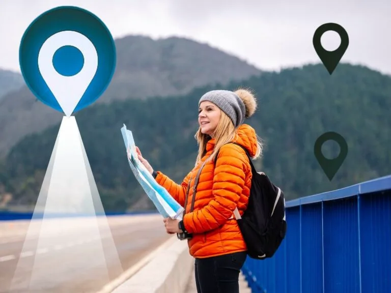 Woman holding map with location pin icons overlooking forested mountains and lake.