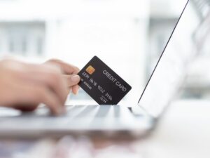 How to convert more visitors to your tourism website - photo of hand holding credit card over laptop