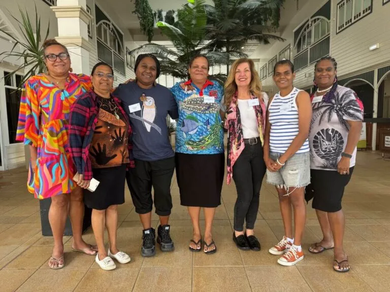 Group of seven tourism operators and DMO representatives posing together indoors at conference.