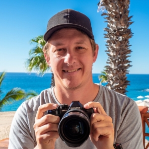 Mark Fitz panellist influencer Photo of Mark Fitz holding a camera in front of a beach