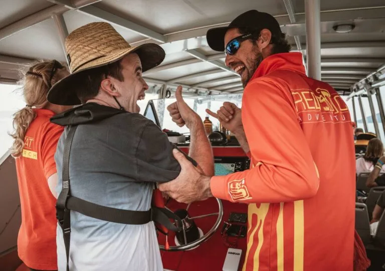Staff member in red jacket interacts with tourist on Whitsunday boat tour.