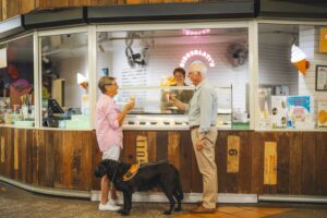 Older couple at ice cream parlour with service dog.