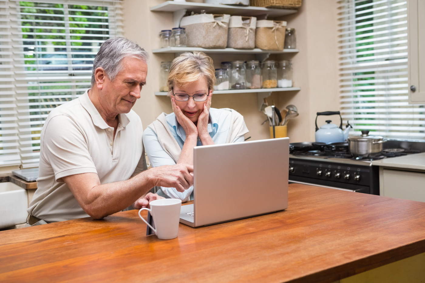 Senior couple using the laptop together at home in the kitchen