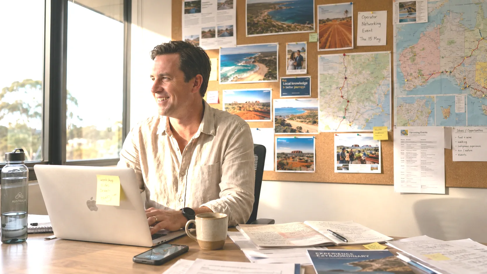 Tourism operator at a desk surrounded by destination photos and a regional map